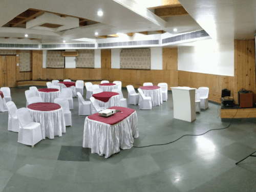 Elegantly set indoor banquet hall with round dining tables and white draping at Kapila Resorts Kharadi Pune