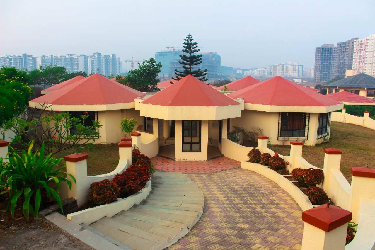 Ground-level view of luxury villa cottages with red conical roofs and landscaped gardens at Kapila Resorts Kharadi Pune