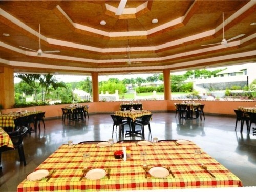 Bright open-air restaurant interior with checkered tablecloths and garden views at Kapila Resorts Kharadi Pune
